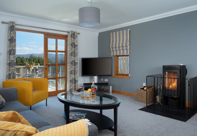Living room with french doors and log burner in self catering property in Aviemore
