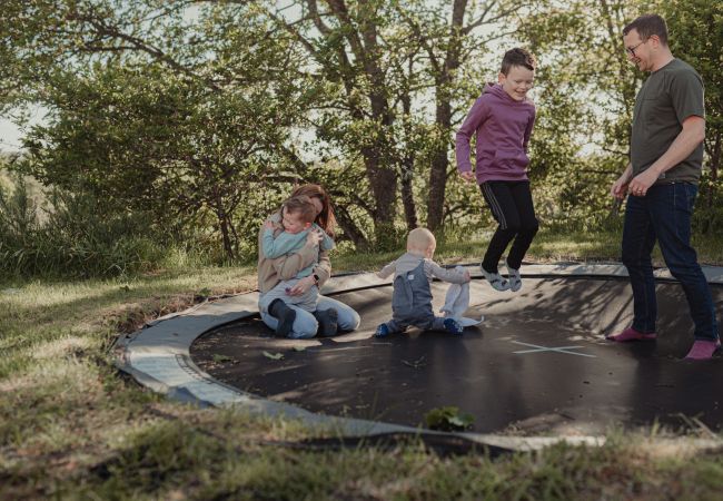 Family plays on a trampoline on holiday in The Cairngorms