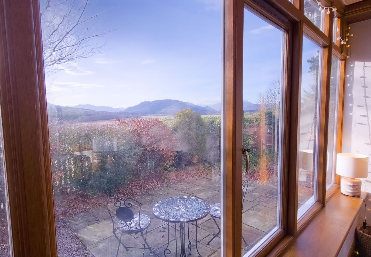 Conservatory with large windows overlooking the Highlands in a holiday home