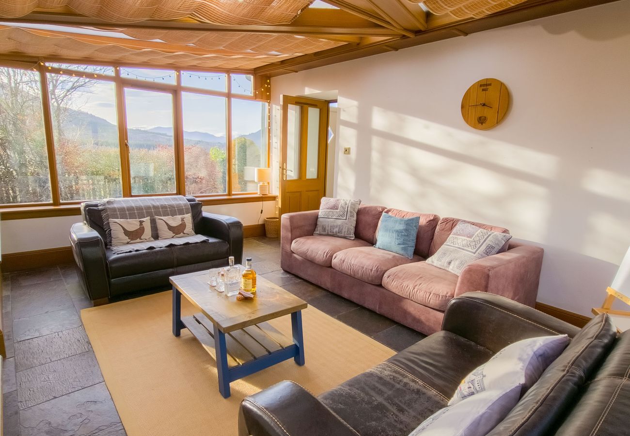 Conservatory with seating and views of the Highlands in a Laggan holiday home.