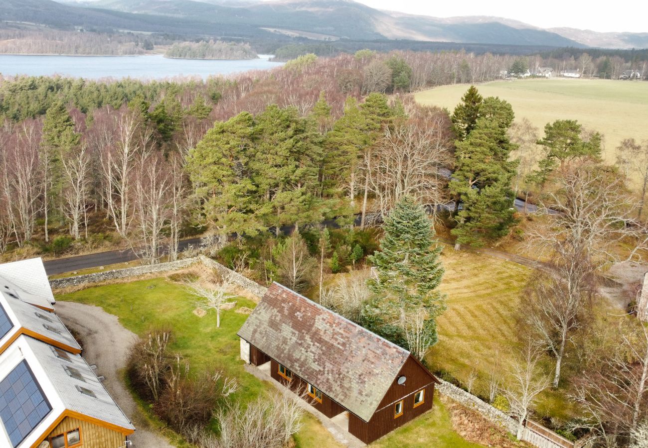 A self catering cottage set beside trees and Loch Insh 