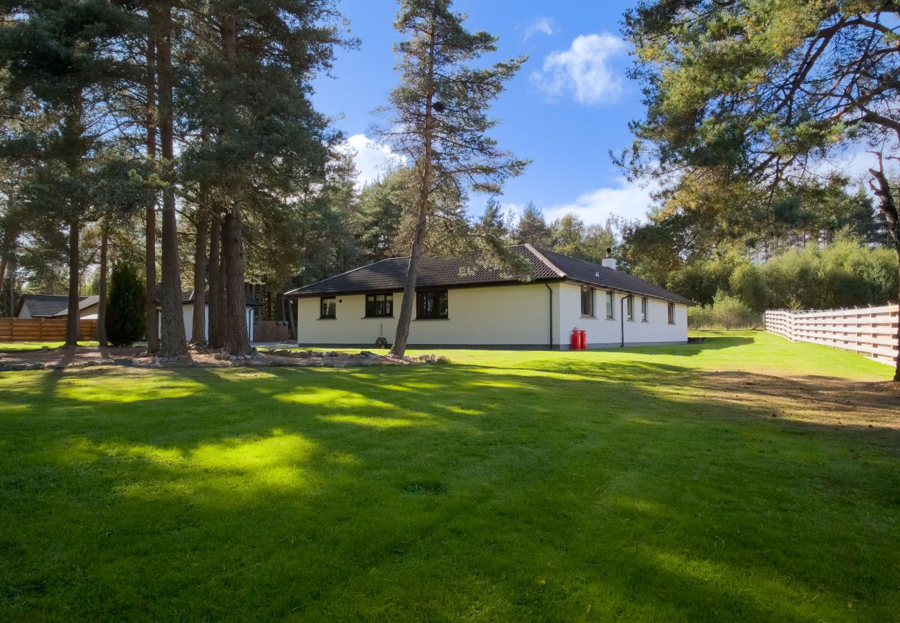 Exterior view of the holiday home with a large garden bordering woodland.