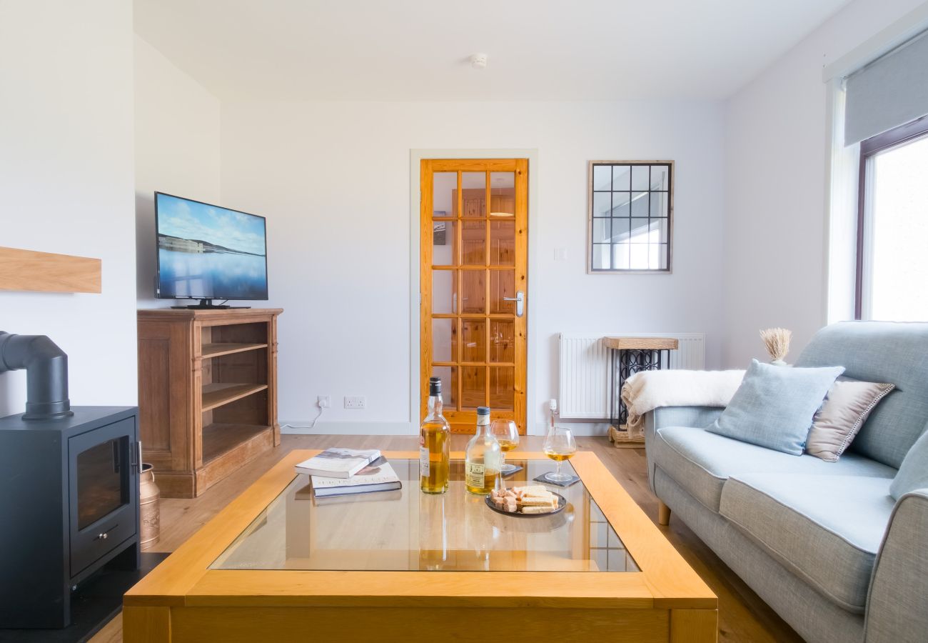 Living room with electric fire, smart TV and wooden coffee table at Lynemore Croft