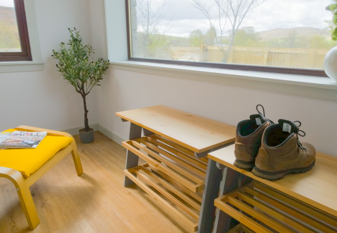 Entrance area with shoe rack, yellow footstool and olive tree with countryside views at Lynemore Croft