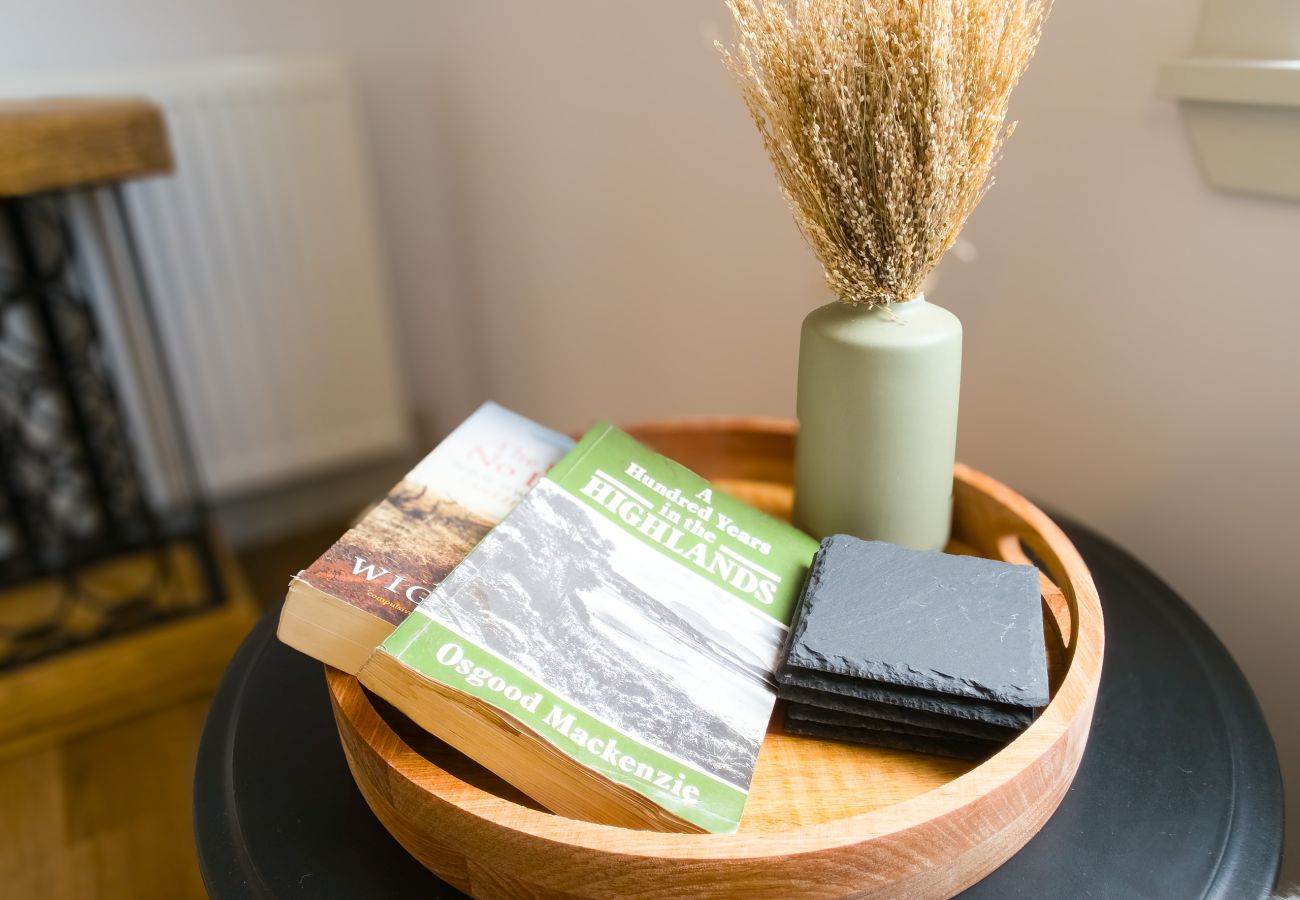 Wooden tray with Highland guidebooks, slate coaster and dried grass vase at Lynemore Croft