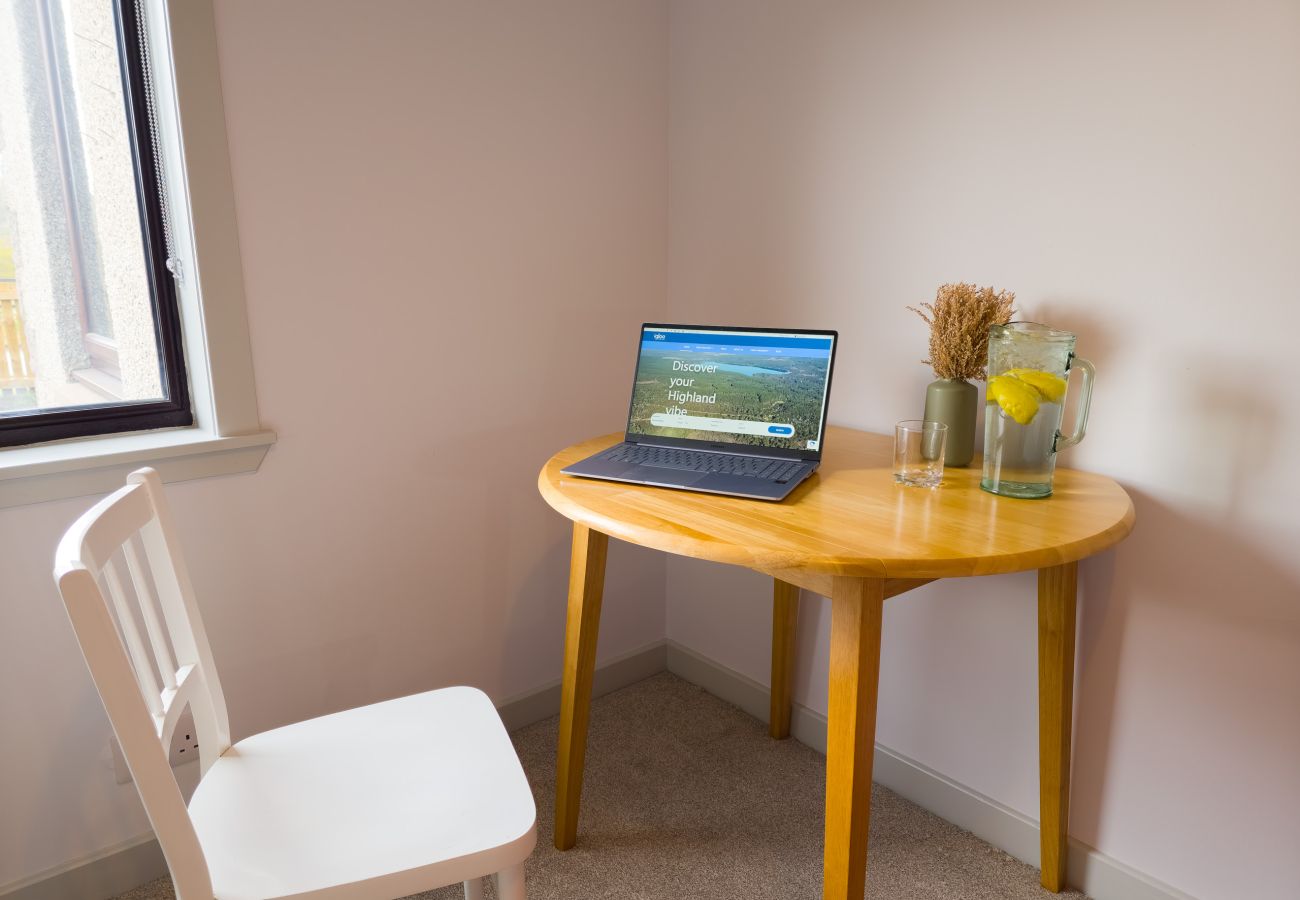 Bedroom with wooden desk, white chair and window in Lynemore Croft holiday cottage