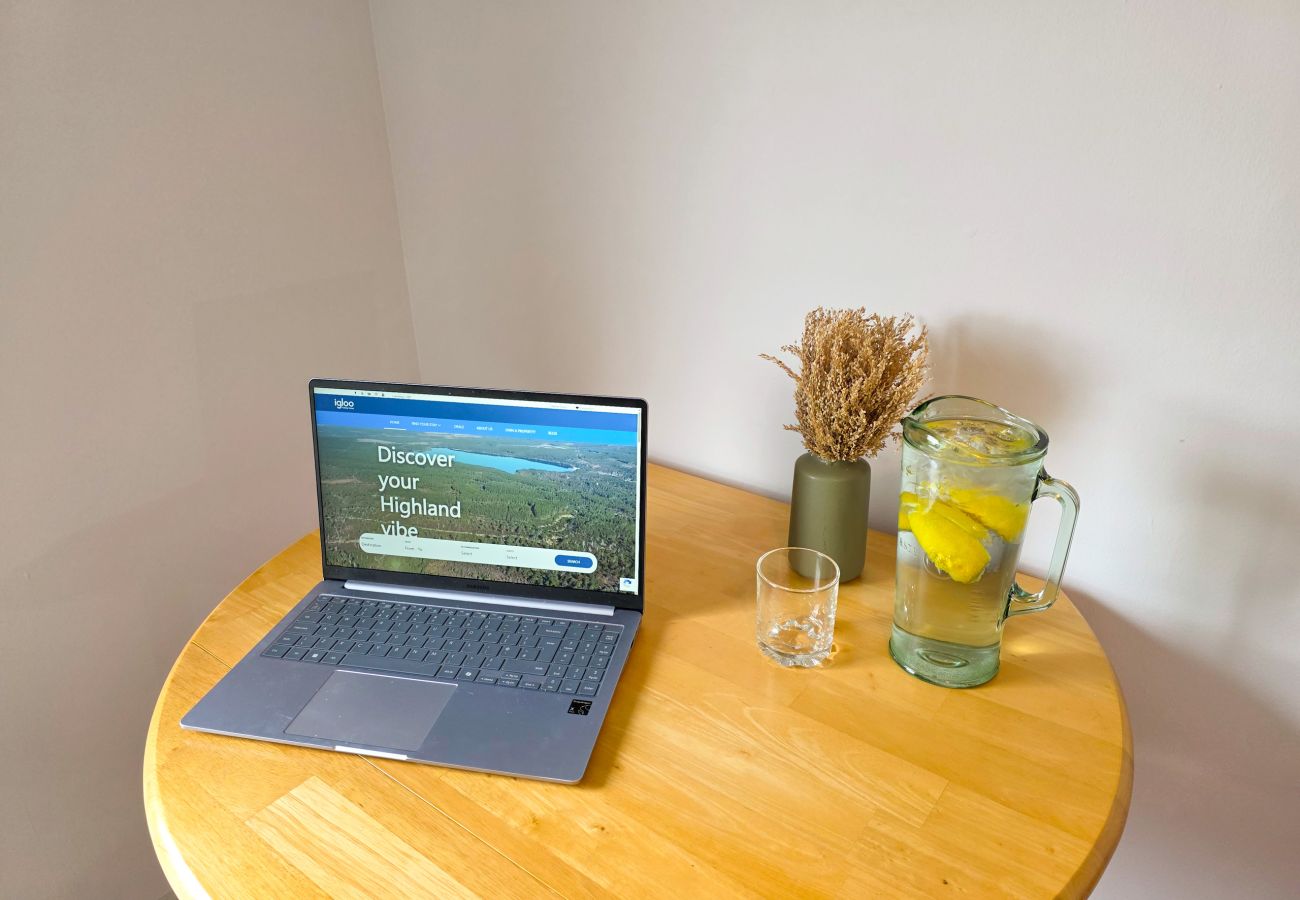Laptop open on circular wooden desk in bedroom at Lynemore Croft Highland cottage
