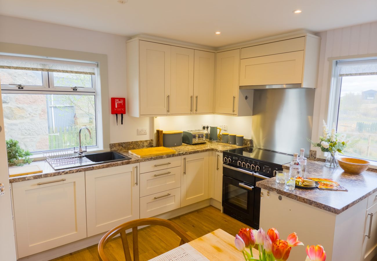 White kitchen with range cooker and garden view at Lynemore Croft