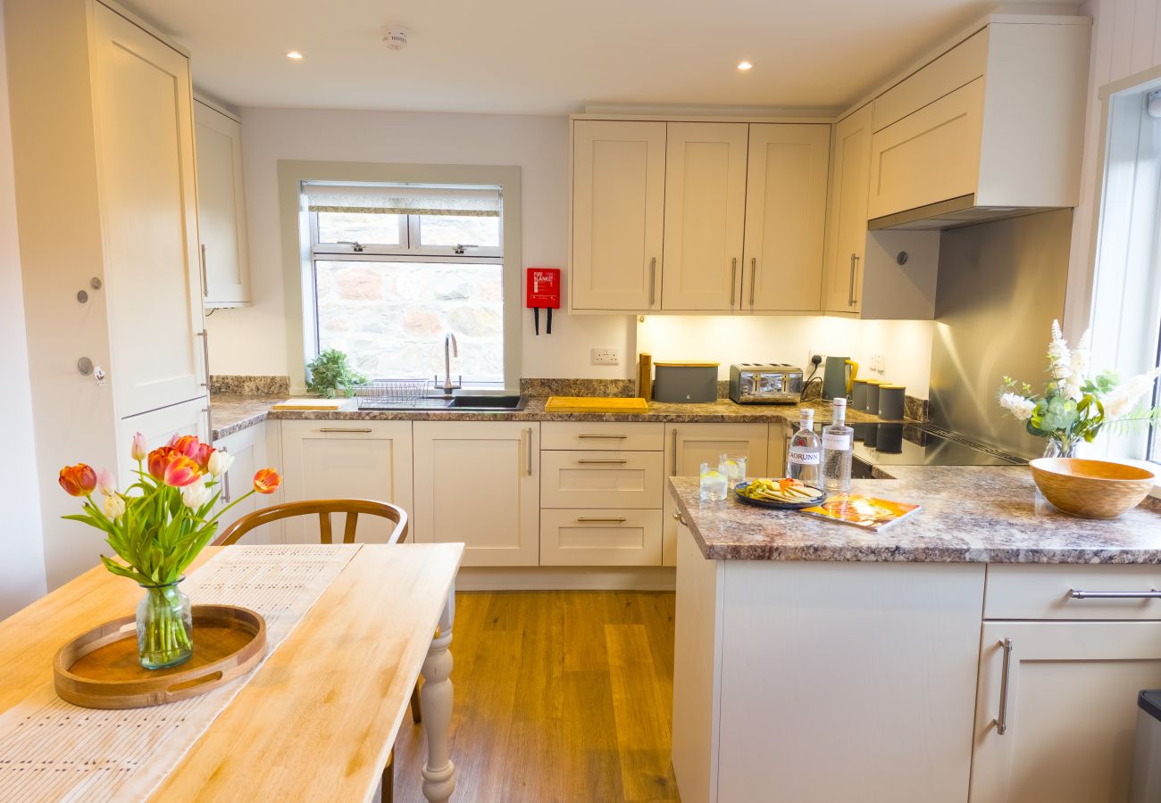 Kitchen with white cabinets and dining table at Lynemore Croft