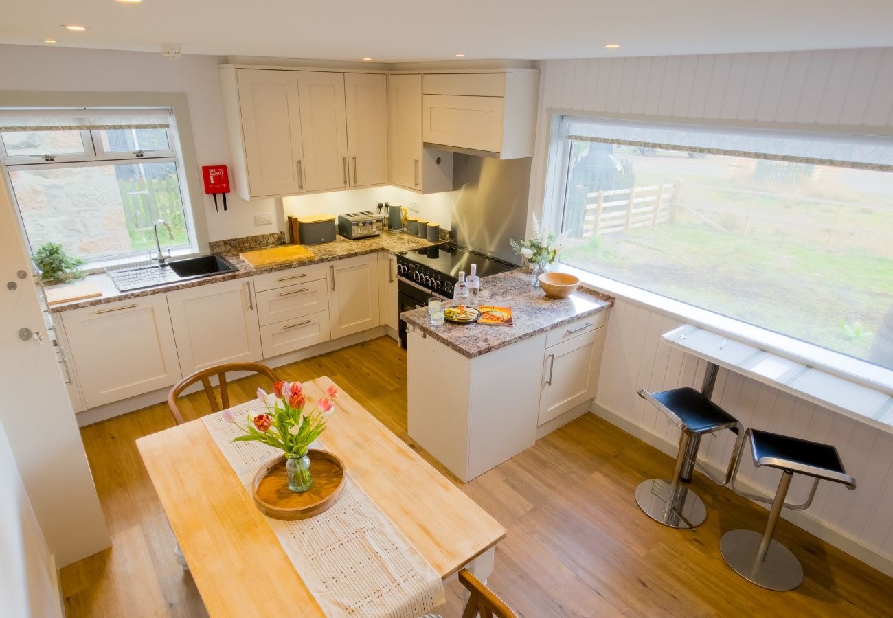 Modern kitchen with white cabinets, granite worktops and dining table at Lynemore Croft