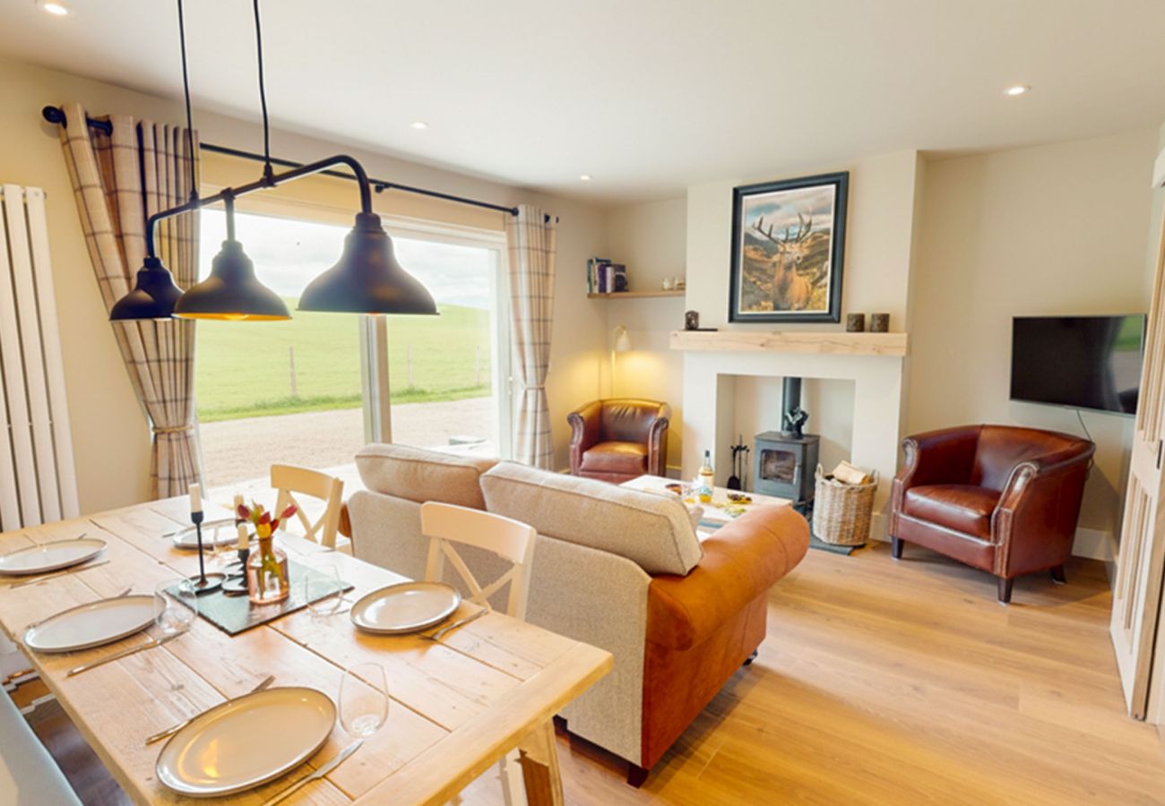 Open plan living and dining room at Betty's Cottage with log burner and Highland views