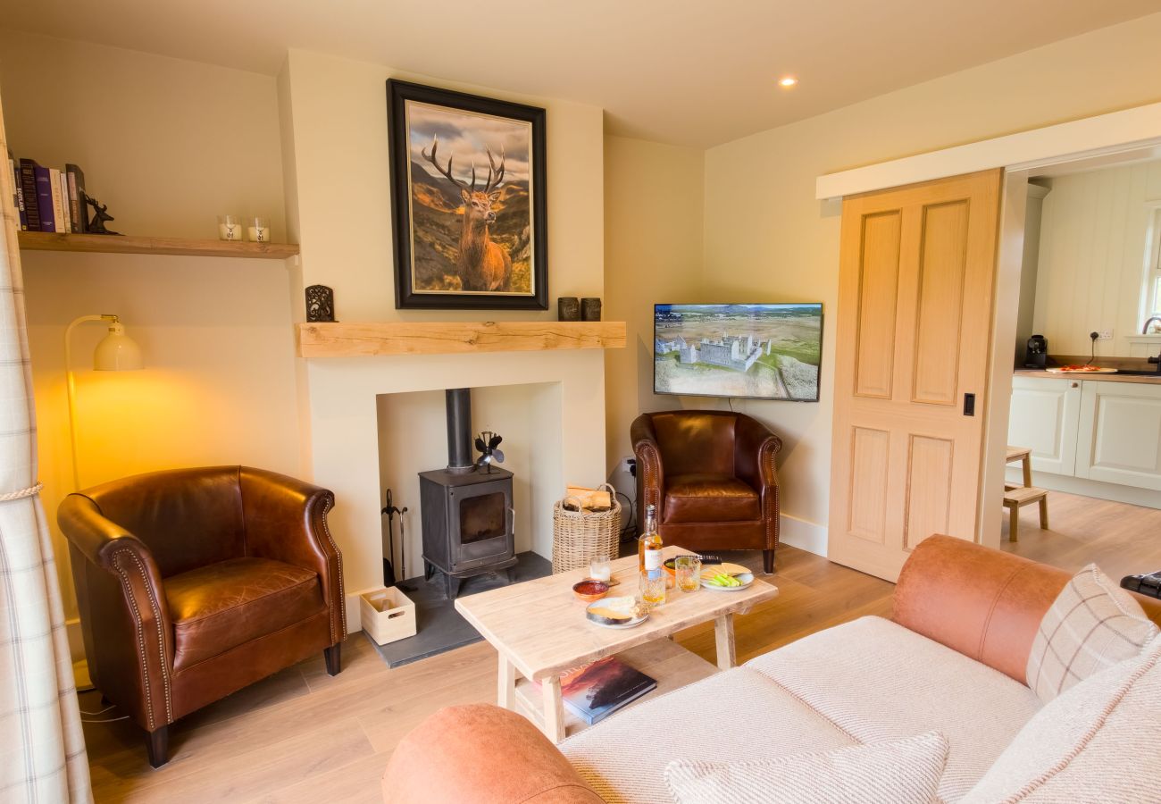 Cosy sitting room at Betty's Cottage with log burner, leather chairs and Highland stag art