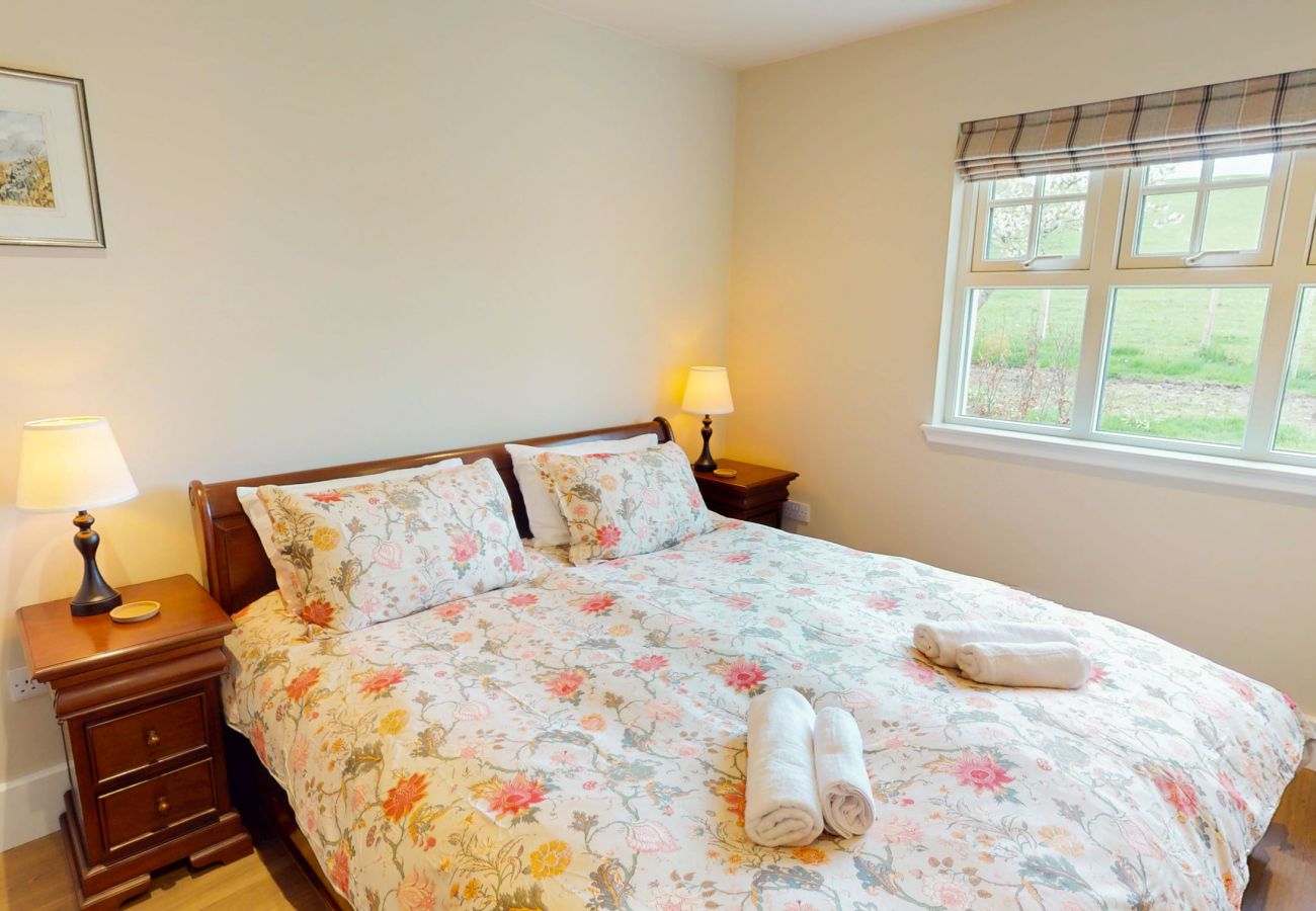 Comfortable bedroom with floral bedding and garden view at Betty's Cottage Highland self-catering