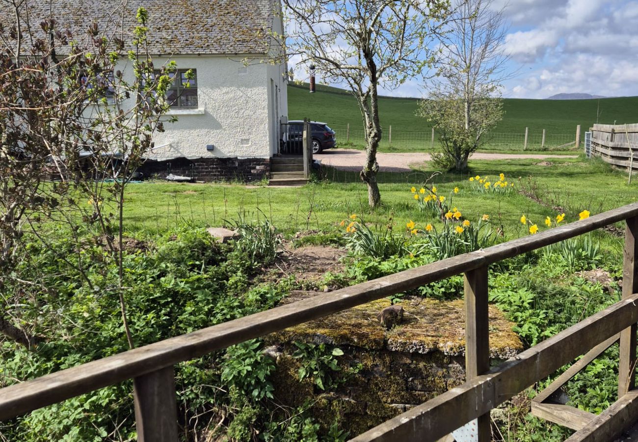 Garden with bridge and cottage exterior at Betty's Cottage, Scottish Highlands