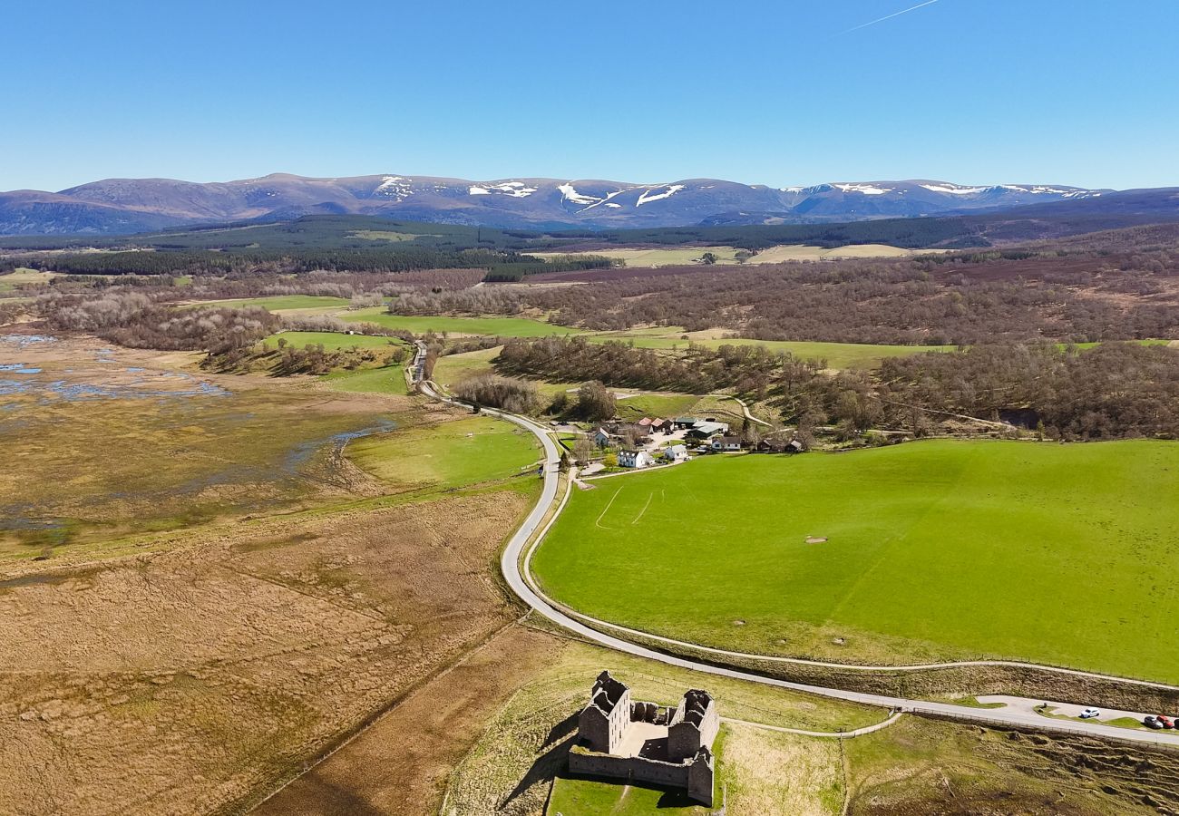 Aerial view of Betty's Cottage with Ruthven Barracks and Cairngorm mountains, Scottish Highlands
