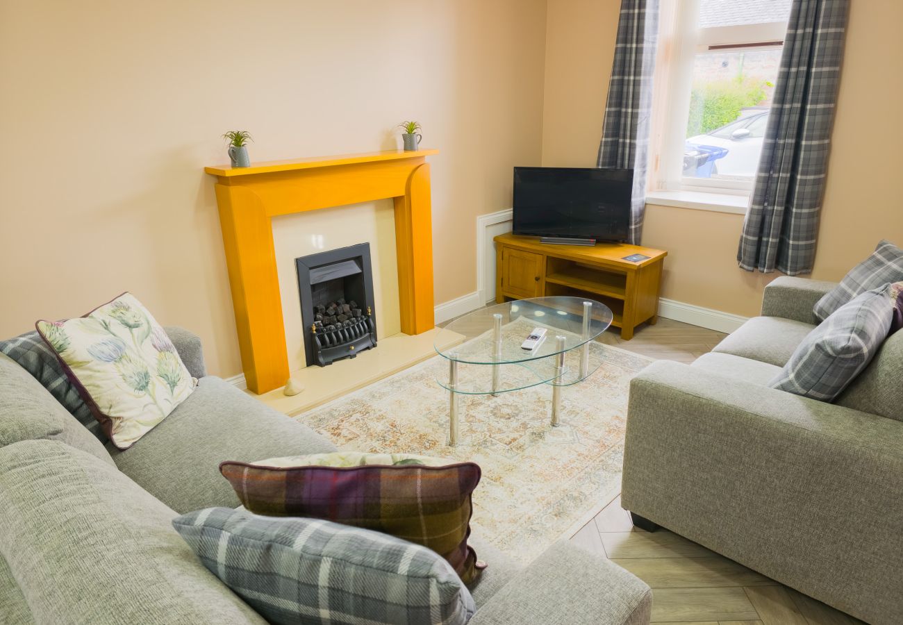 Cosy lounge with tartan sofas and fireplace at Inverness Crown holiday let
