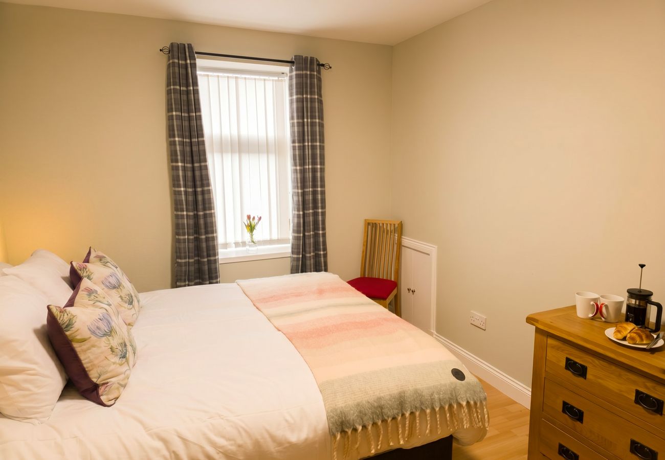 Double bedroom with pink tones and wooden floor at Inverness holiday rental