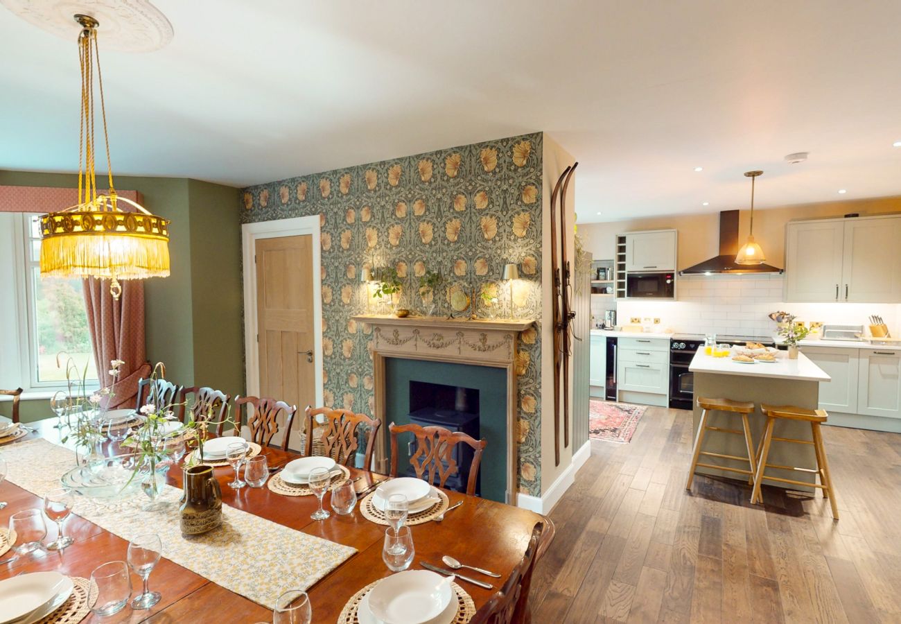 Elegant dining room with large table, chandelier and fireplace at Lynwilg House Highland holiday home
