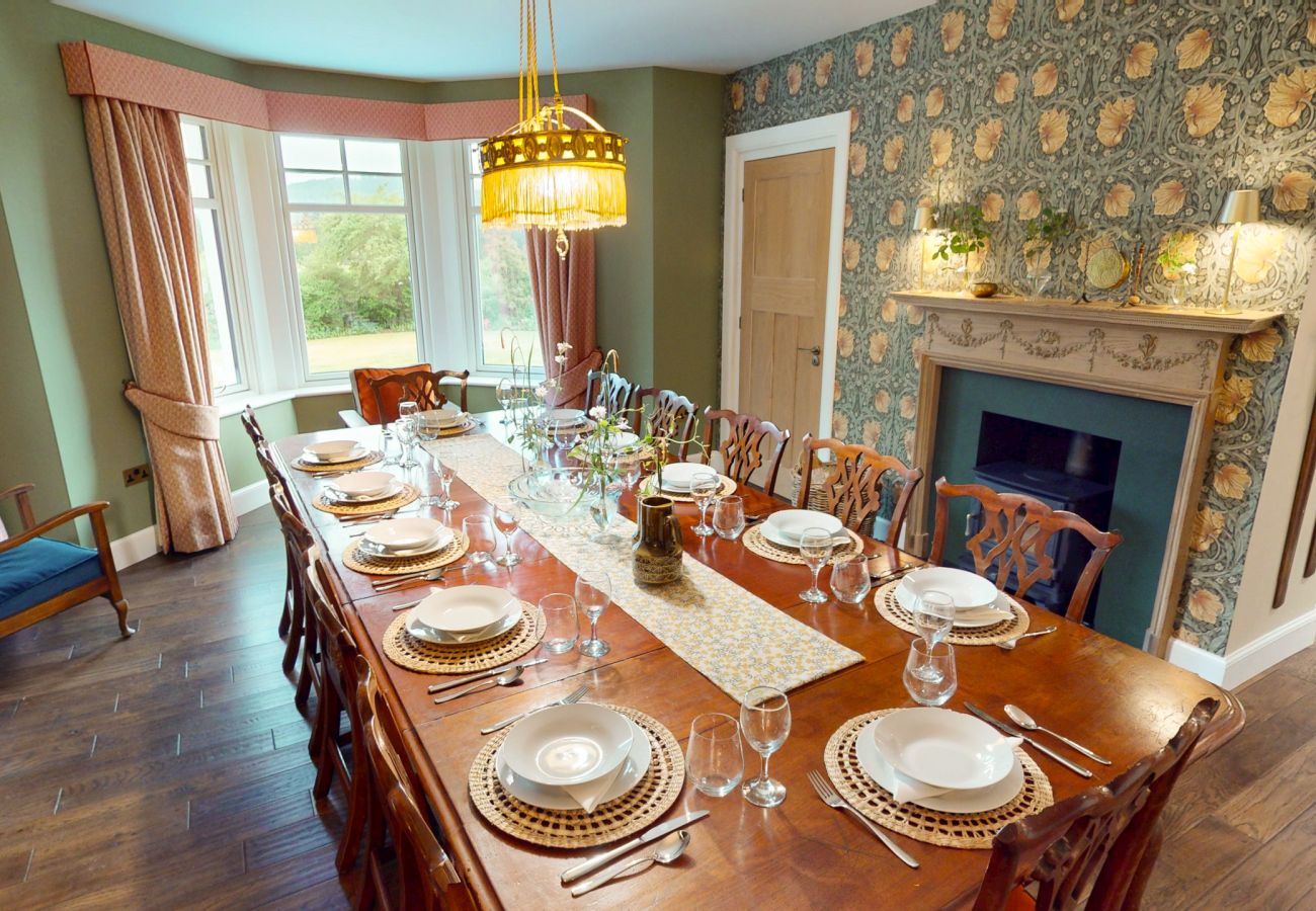 Dining room with bay window, long table and garden views at Lynwilg House Highland holiday home