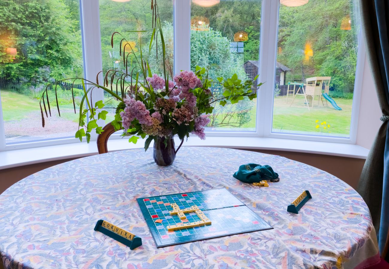 Bay windows with lush garden views in the living room at Lynwilg House Highland holiday home