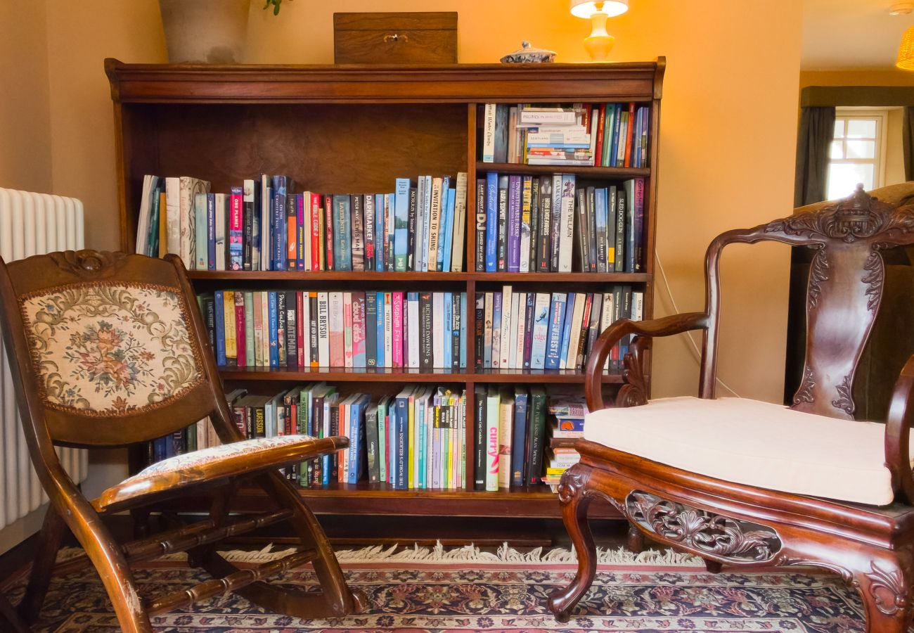 Cosy reading corner with large bookcase and armchairs at Lynwilg House Highland group holiday home