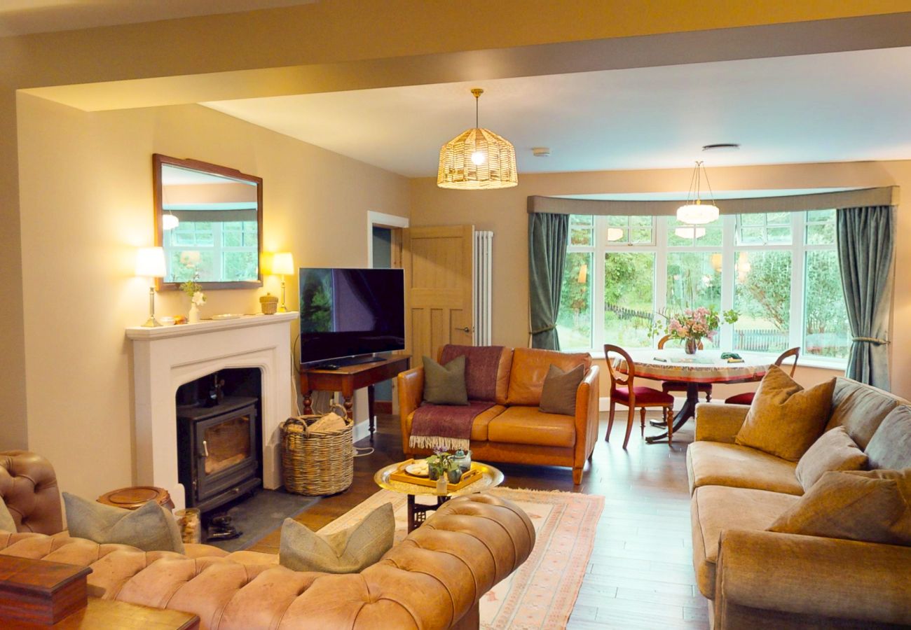 Cosy living room with log burner fireplace, leather sofas and large windows at Lynwilg House