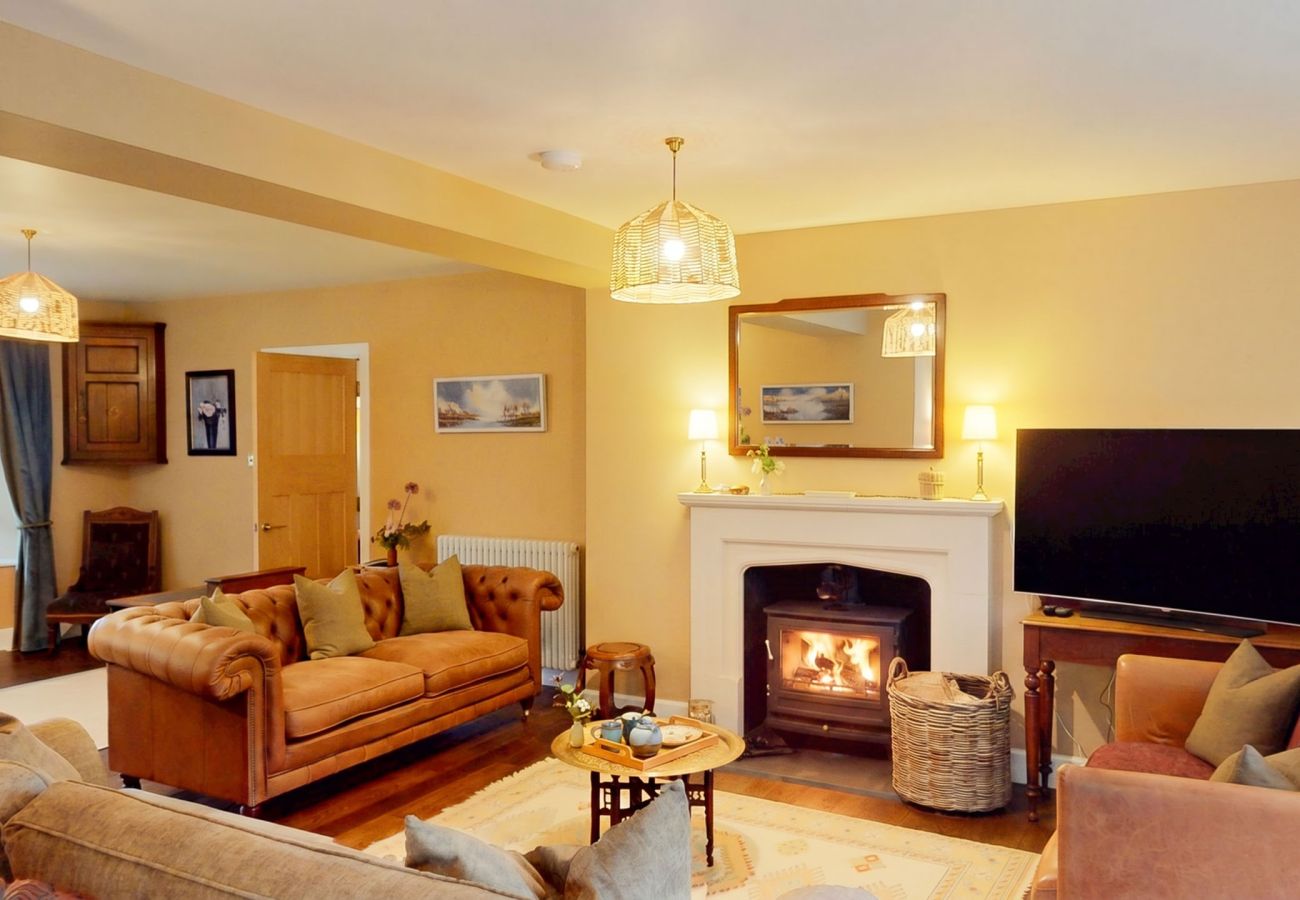 Comfortable sitting room with fireplace, leather sofas and TV at Lynwilg House Highland holiday home