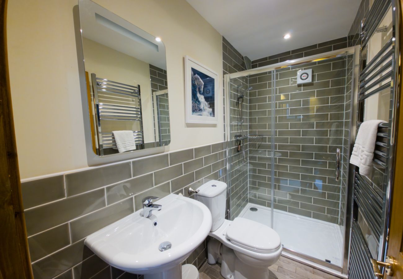 Tiled bathroom with walk-in shower, basin and heated towel rail at Wildcat Lodge in the Cairngorms