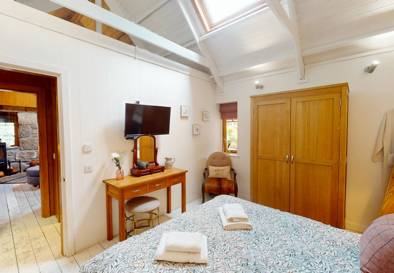 Bedroom with dressing table and wardrobe opening onto the living room at Wildcat Lodge, Boat of Garten