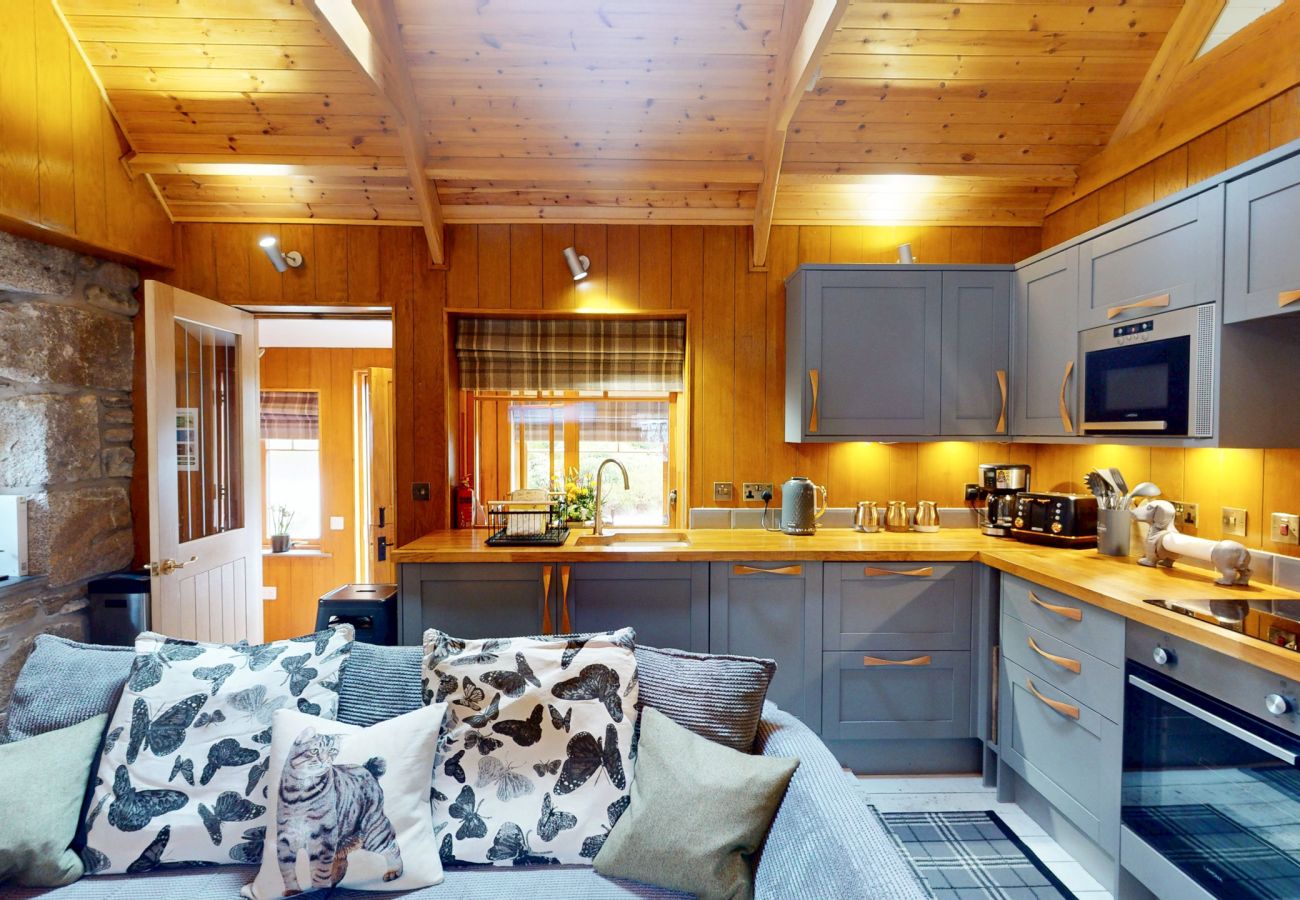 Cushioned sofa looking through to the open-plan kitchen at Wildcat Lodge near Boat of Garten, Cairngorms