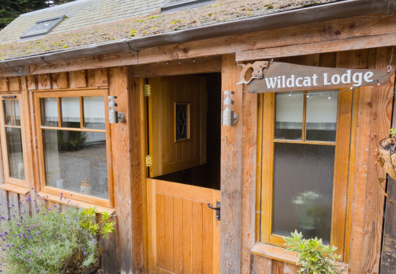 Timber stable door and painted Wildcat Lodge sign at the front entrance of the lodge in the Cairngorms
