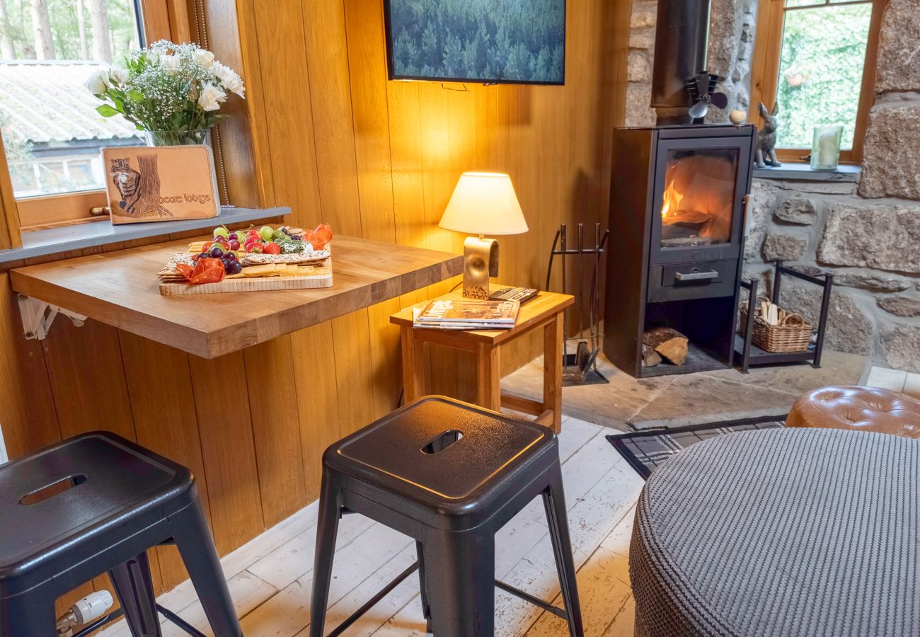 Breakfast bar with stools beside a lit wood burning stove inside Wildcat Lodge near Boat of Garten