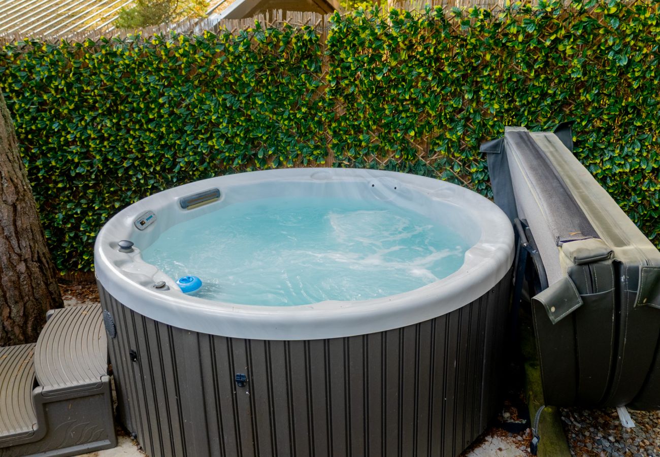 Private outdoor hot tub screened by ivy and pine trees at Wildcat Lodge, Boat of Garten, Cairngorms
