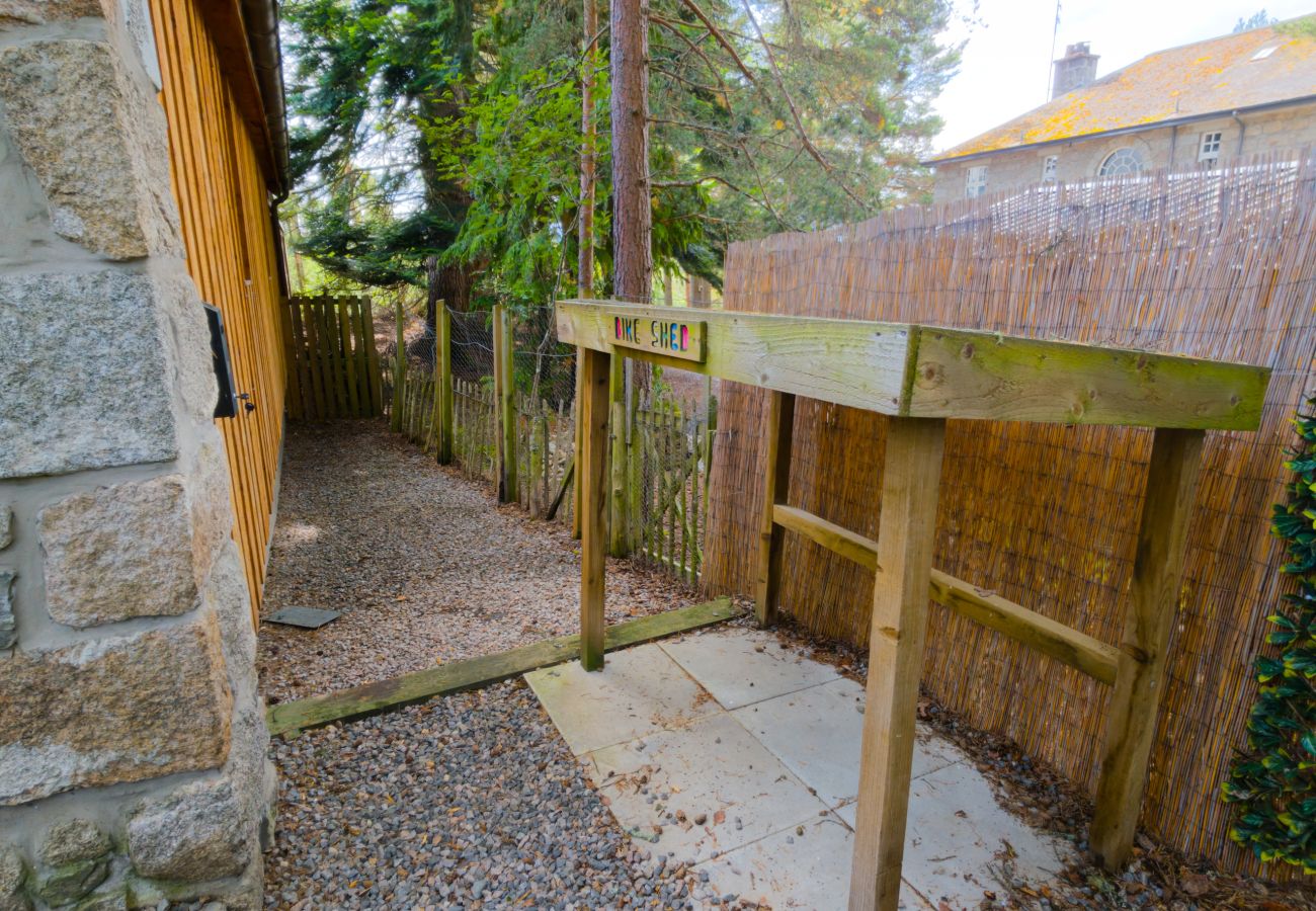 Covered timber shelter and gravel path along the side of Wildcat Lodge in the Cairngorms
