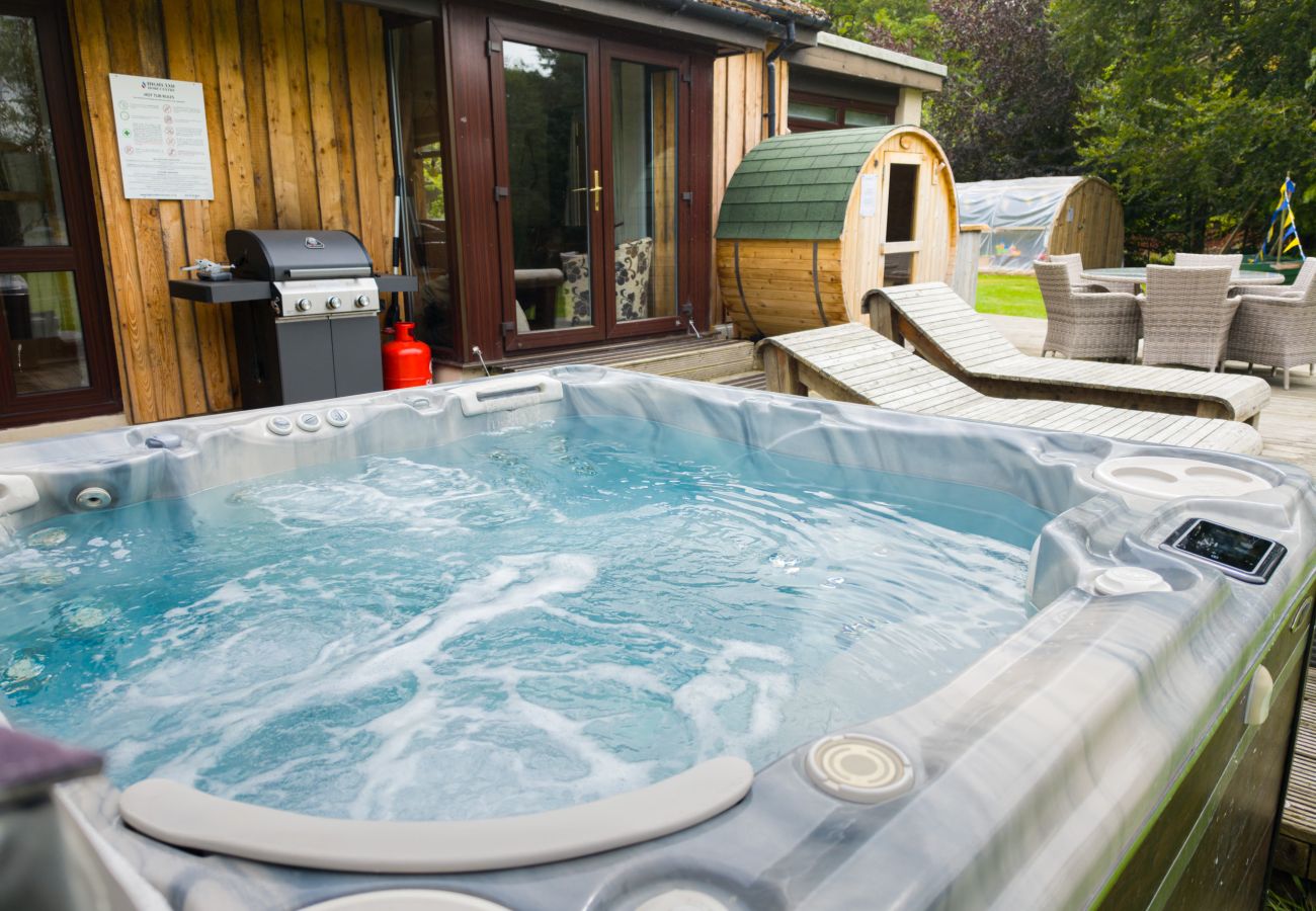 Bubbling outdoor hot tub with barrel sauna and barbecue at Kinloch Lodge, Balnain near Drumnadrochit