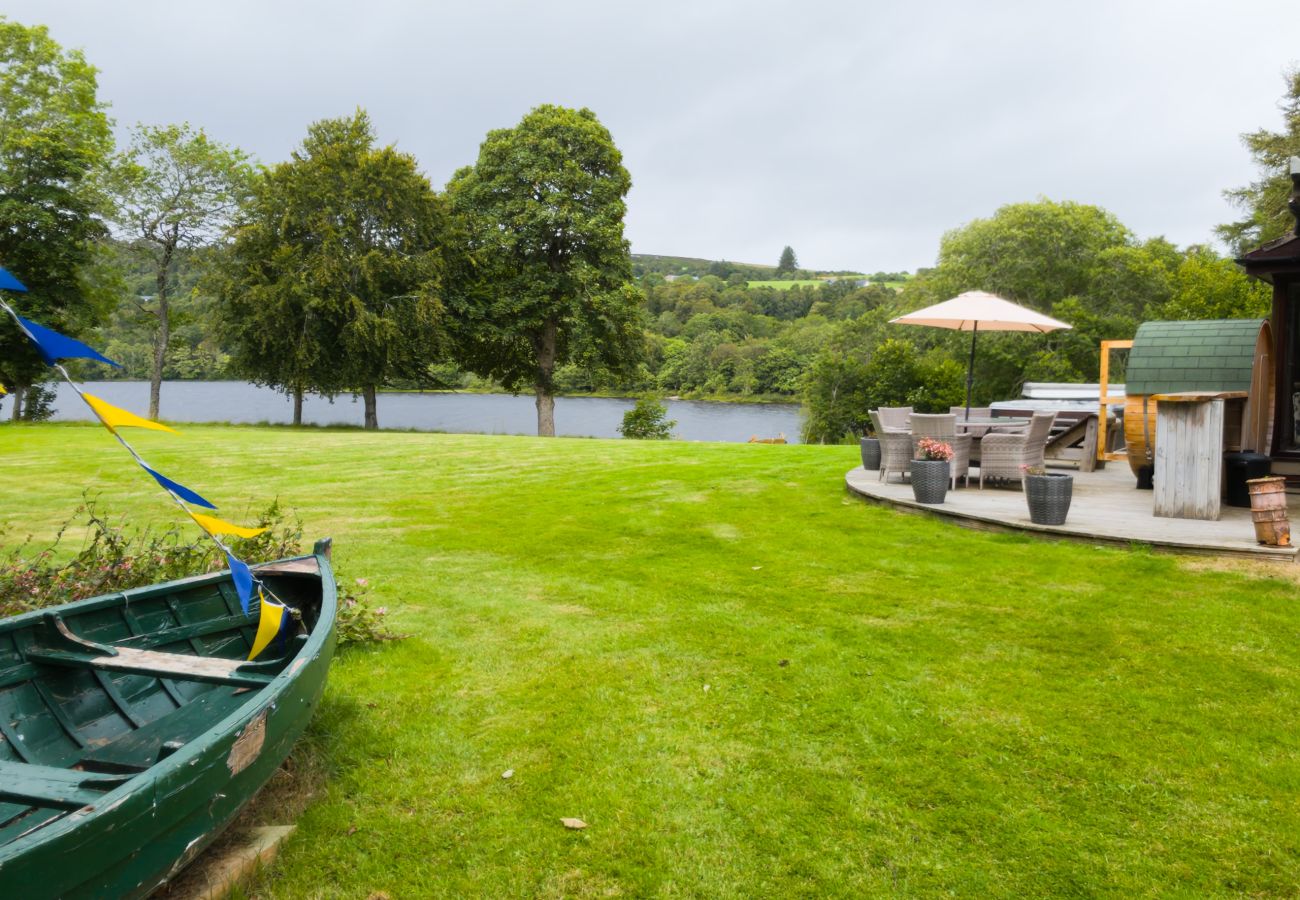 Open lawn between the rowing boat and the decking with the loch beyond at Kinloch Lodge, Balnain