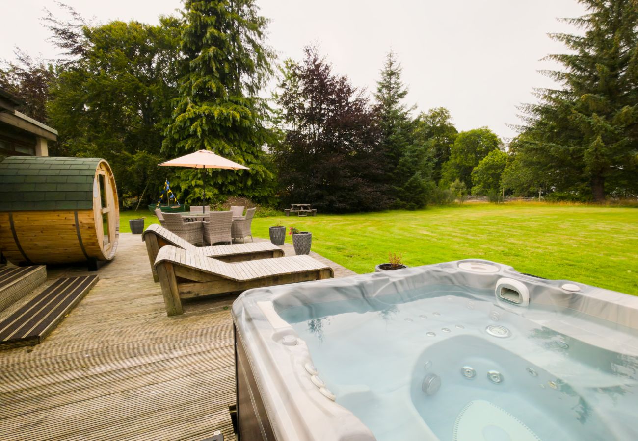 View from the hot tub across the decking to the barrel sauna and lawn at Kinloch Lodge, Balnain