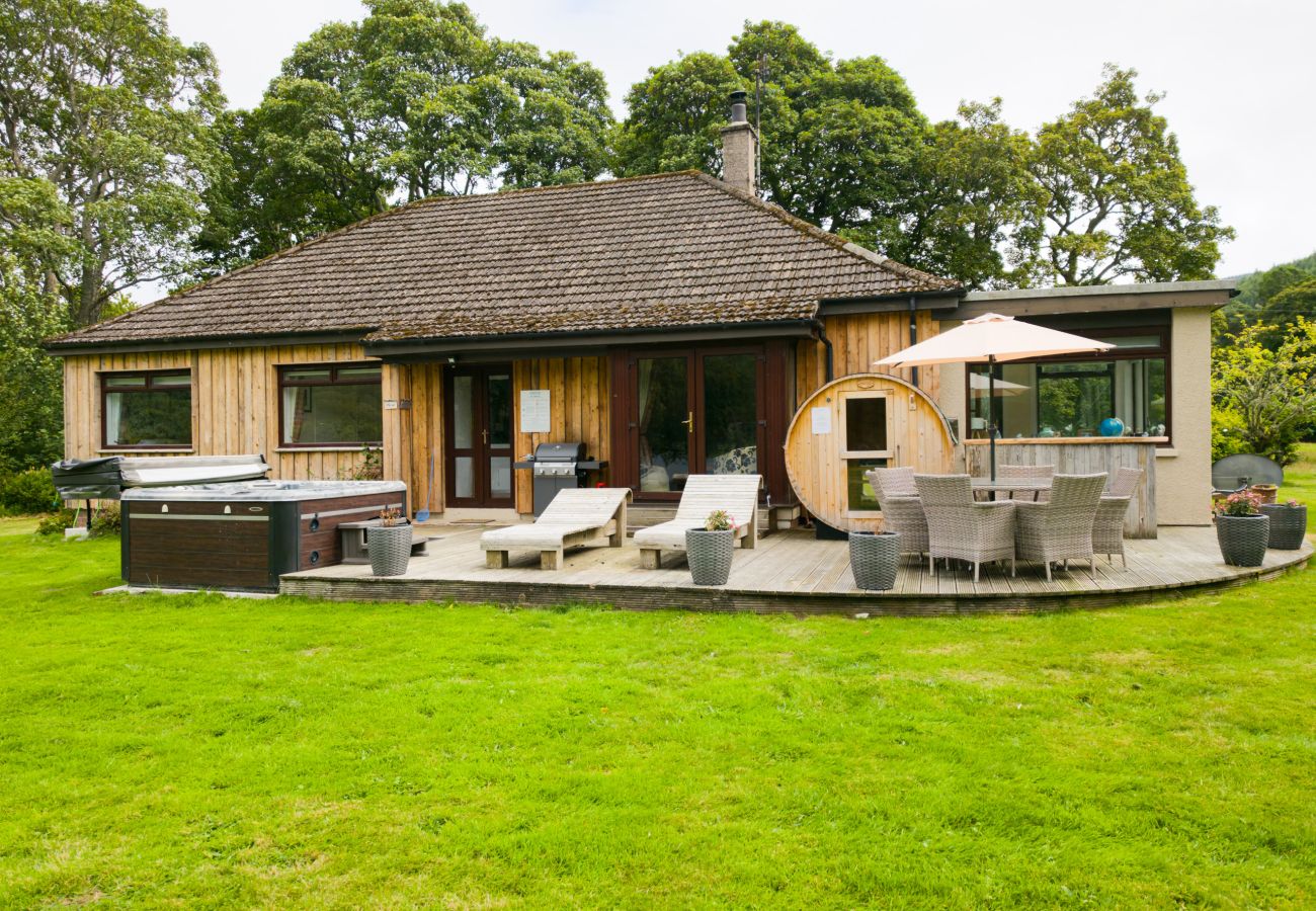 Timber lodge with hot tub, sun loungers and barrel sauna on the decking at Kinloch Lodge, Balnain