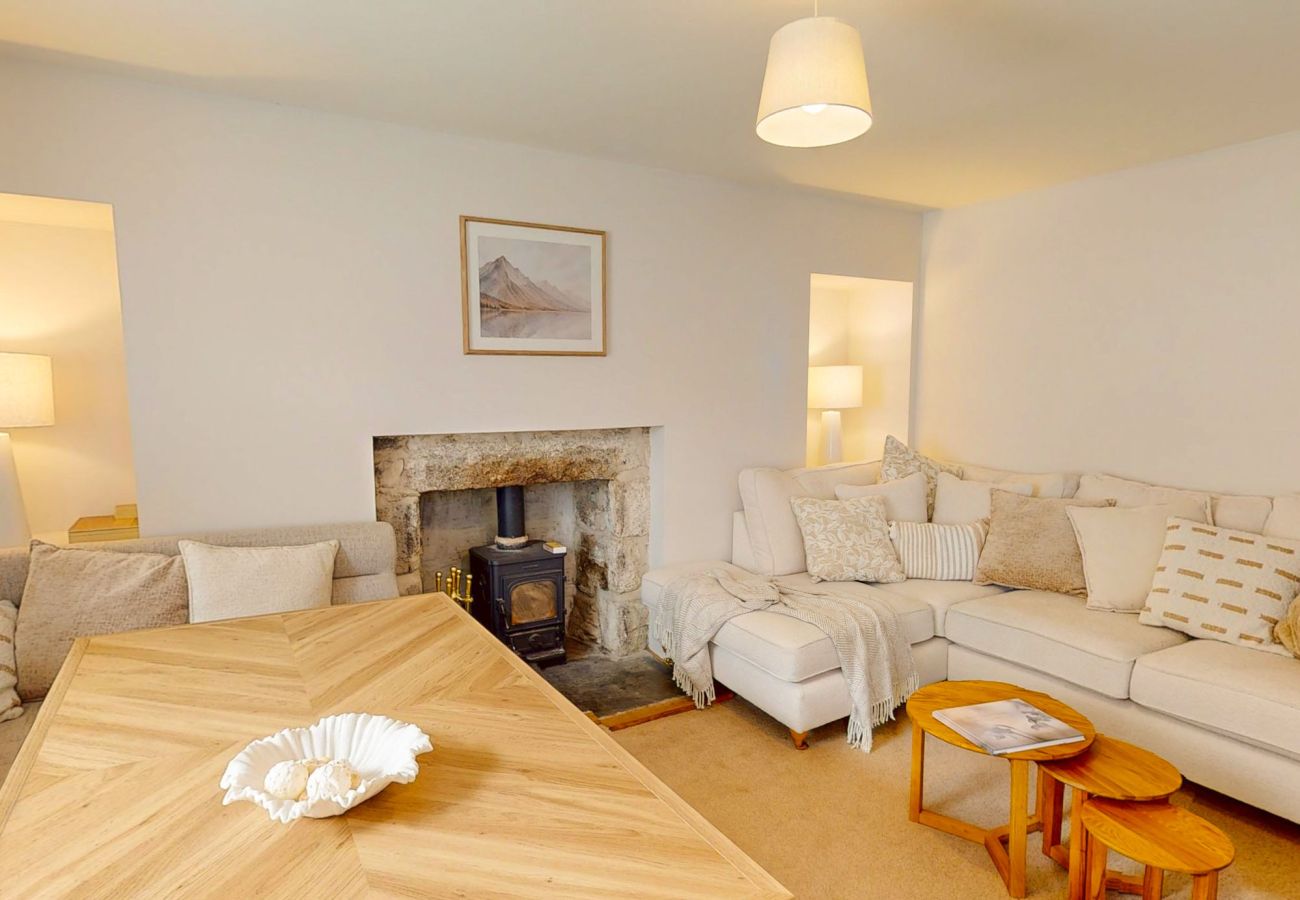 Cream sofas either side of a stone fireplace and wood burner at Twinflower townhouse, Grantown-on-Spey