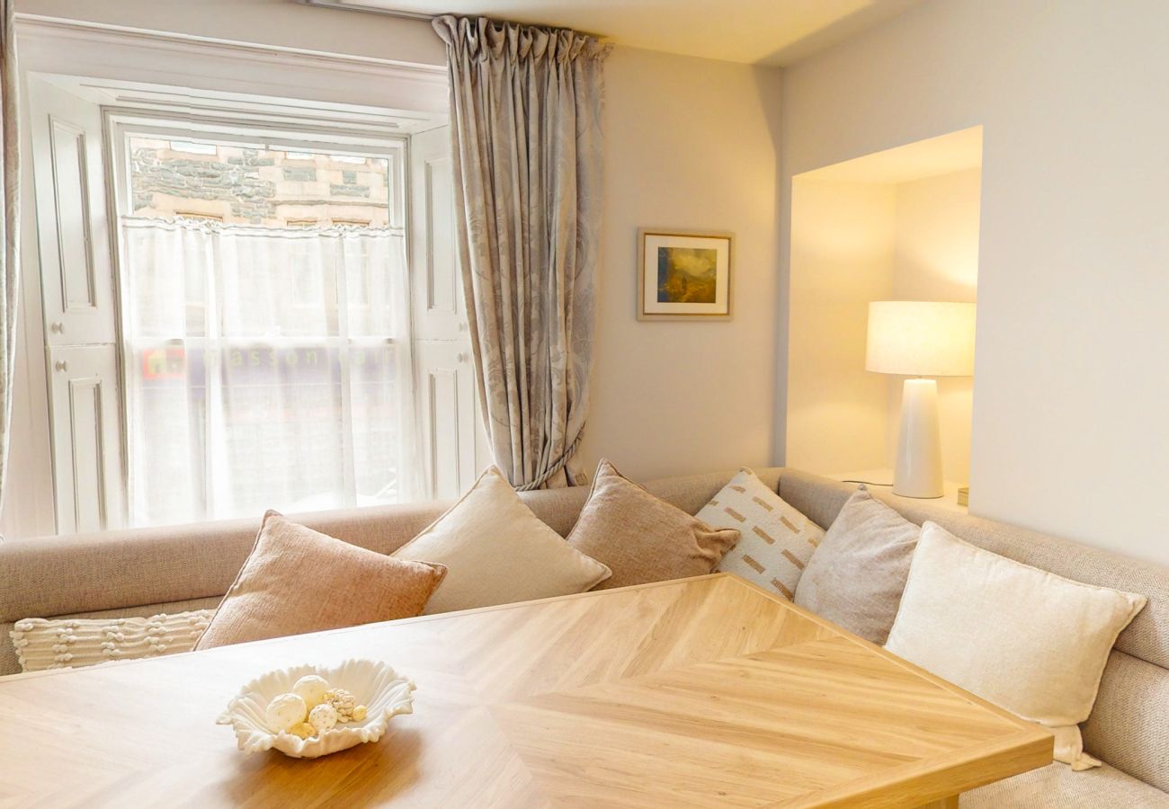 Dining table with cushioned bench seating by the sash window at Twinflower townhouse, Grantown-on-Spey