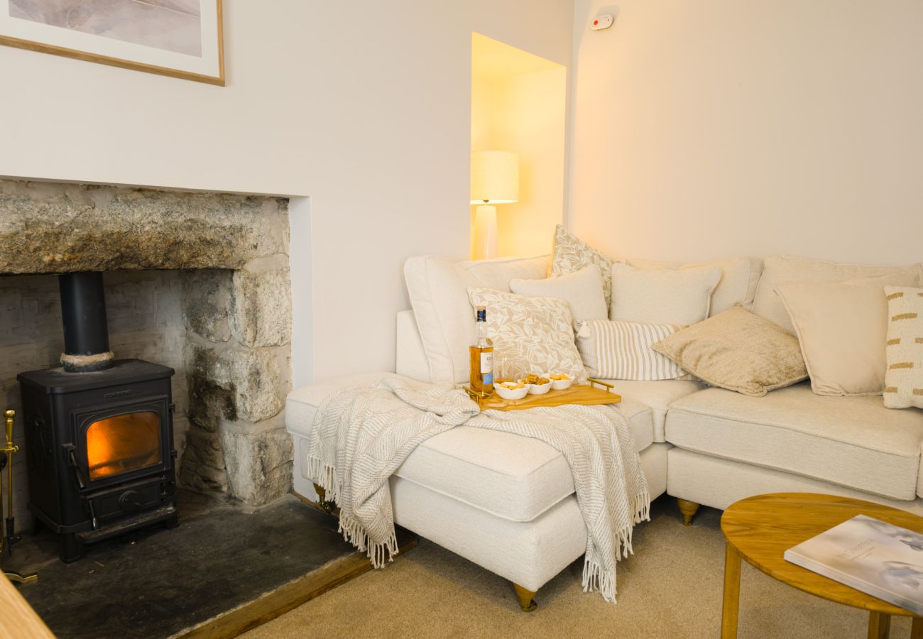 Lit wood burner beside a cream sofa with throw at Twinflower, High Street, Grantown-on-Spey in Strathspey