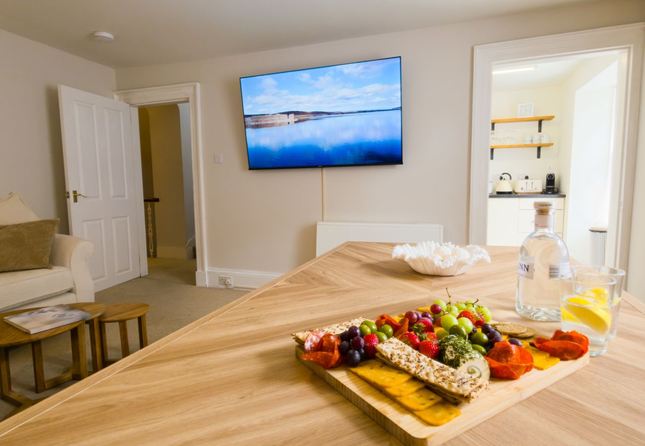 Dining table with grazing board and wall-mounted television at Twinflower townhouse, Grantown-on-Spey