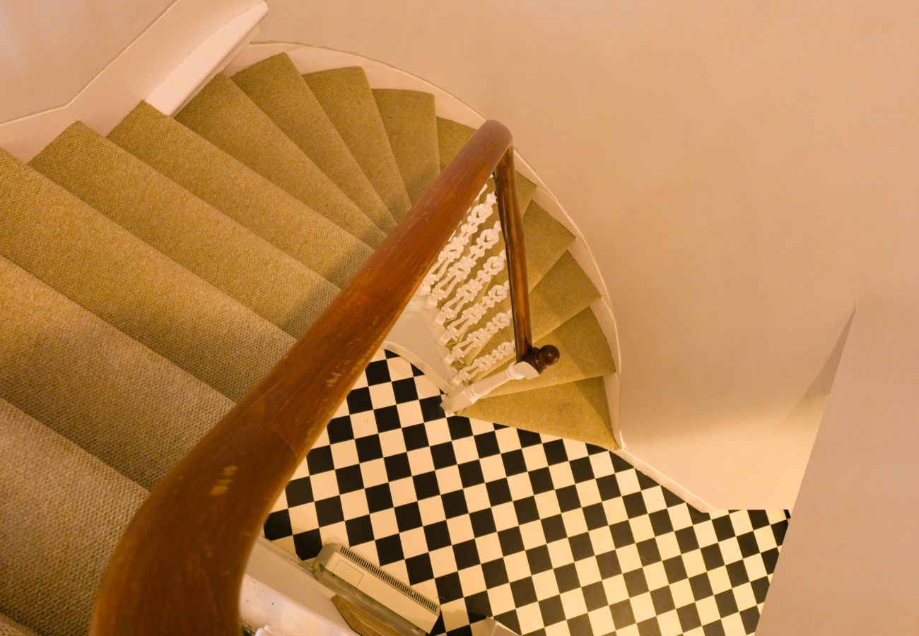 Carpeted staircase and wooden banister above a tiled hall floor at Twinflower, Grantown-on-Spey