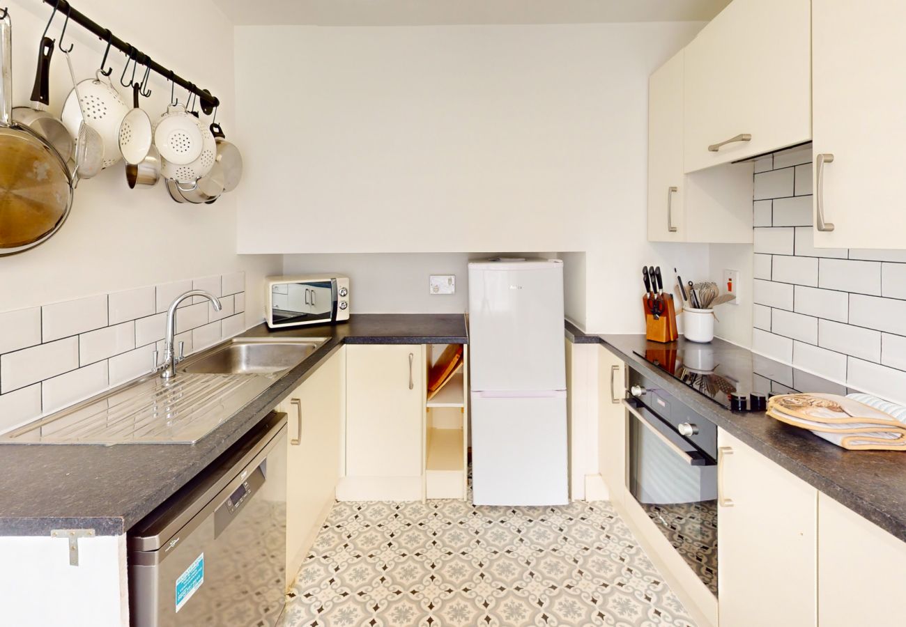 Galley kitchen with hanging pans, sink and dishwasher at Twinflower townhouse, Grantown-on-Spey