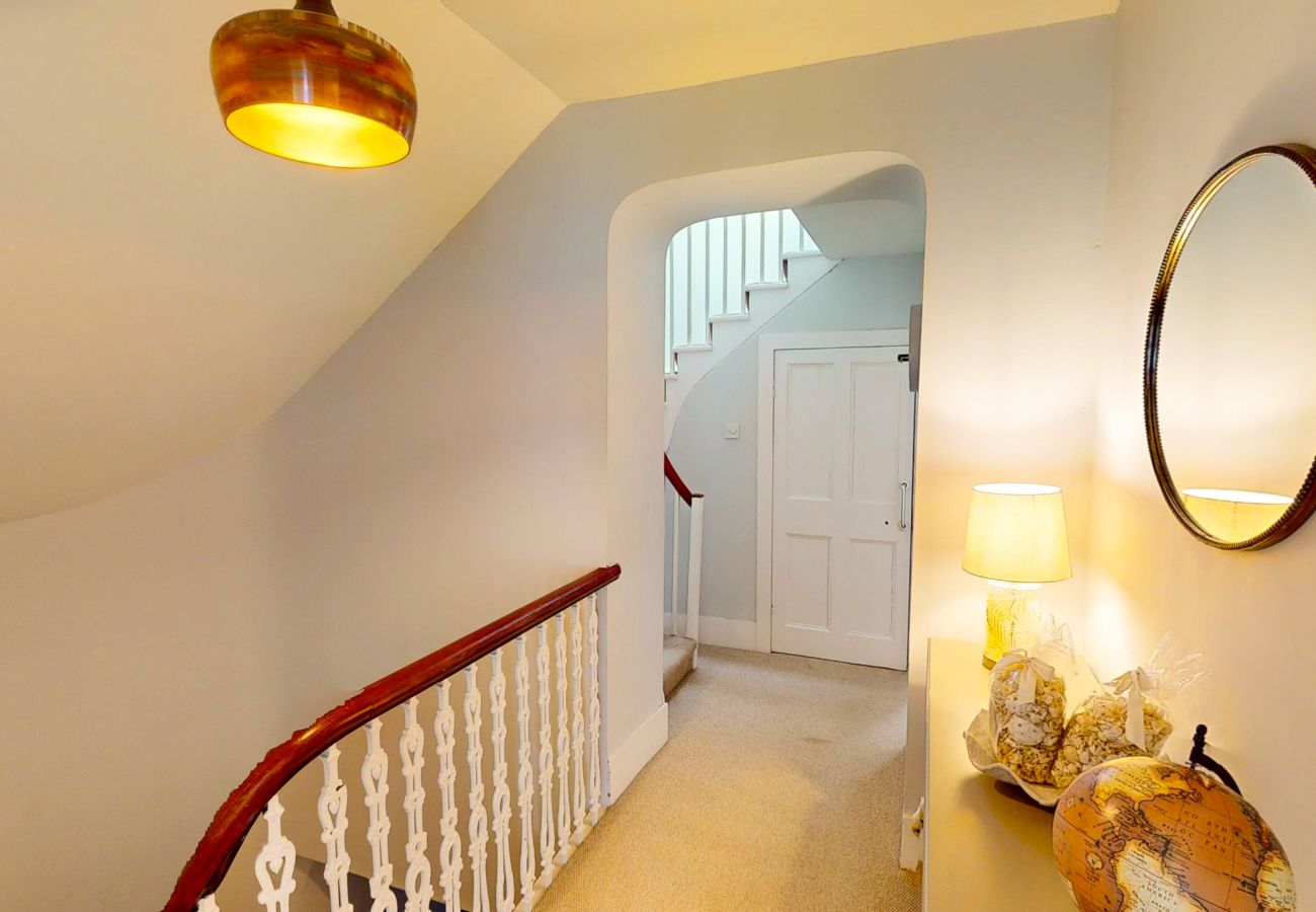 Upstairs landing with banister, round mirror and bedroom doors at Twinflower, Grantown-on-Spey