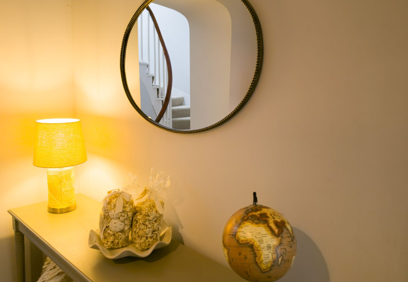 Lamp, globe and ornaments on a console table under a round mirror at Twinflower, Grantown-on-Spey