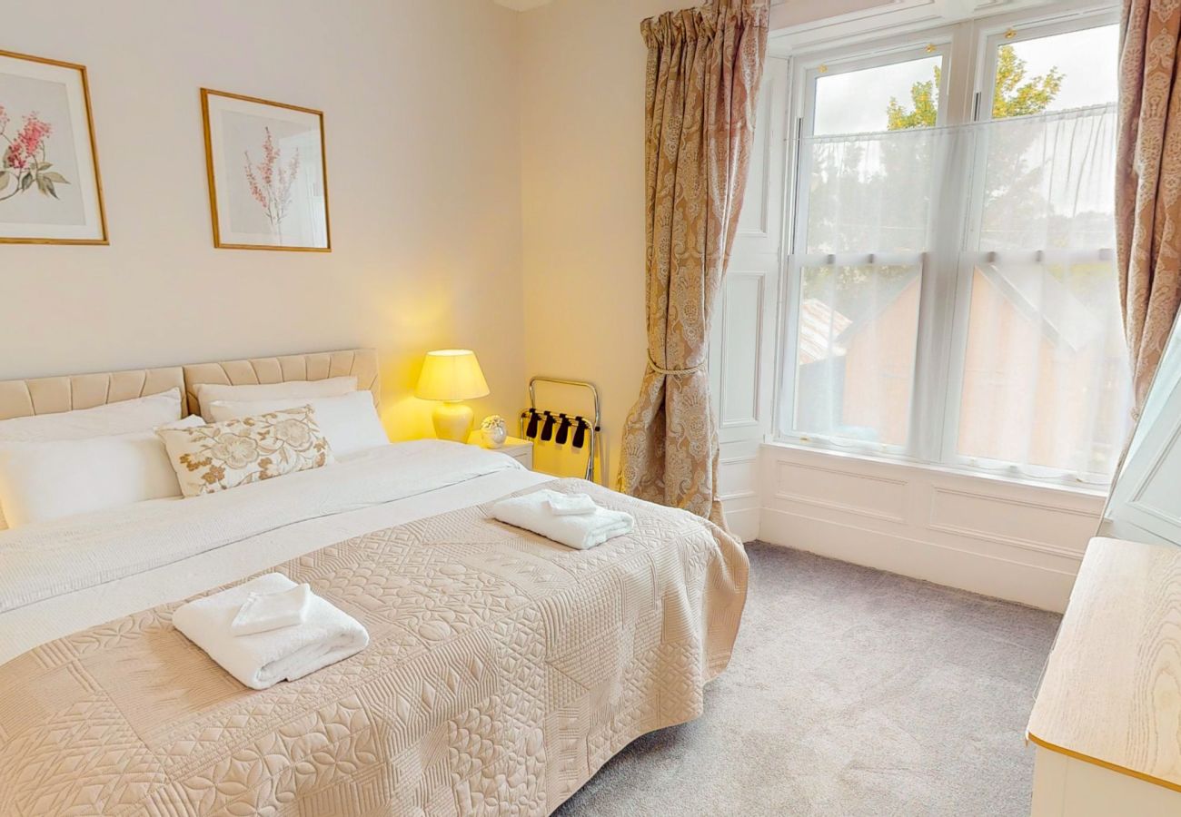 Double bedroom with tall sash windows and botanical prints at Twinflower, Grantown-on-Spey, Cairngorms