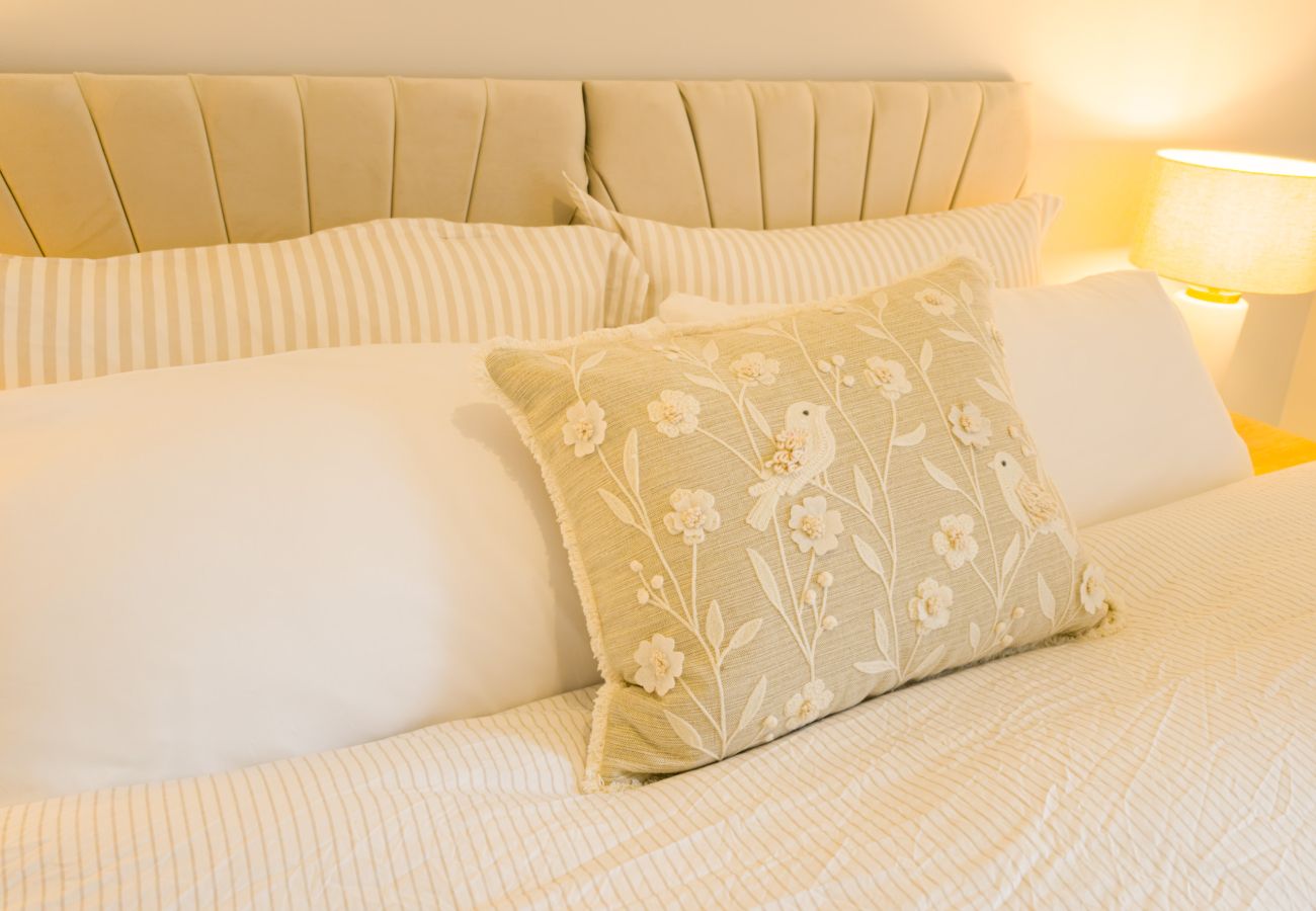 Embroidered bird cushion against the pillows in a bedroom at Twinflower, Grantown-on-Spey, Cairngorms