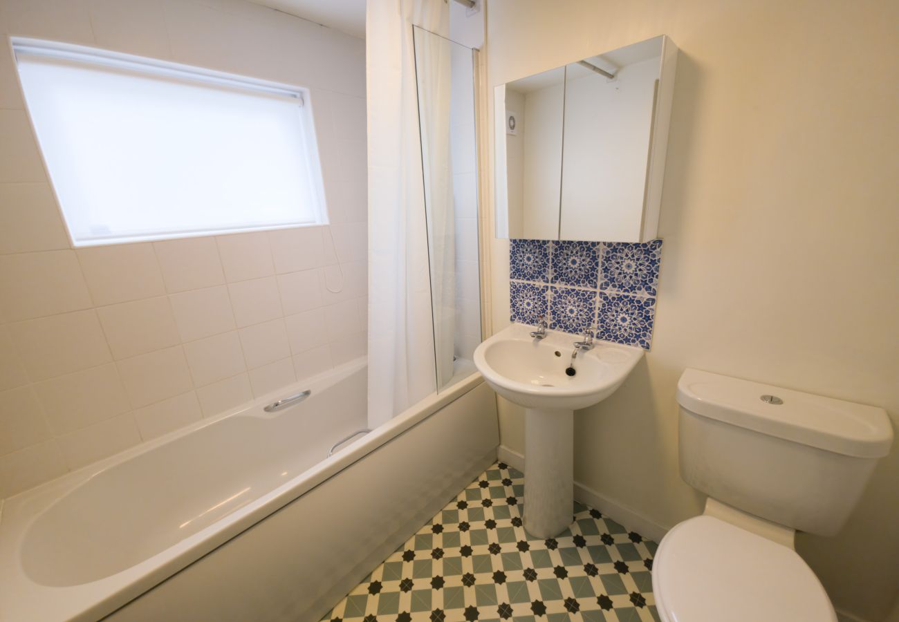 Bathroom with bath, shower over, pedestal basin and mirrored cabinet at Twinflower, Grantown-on-Spey