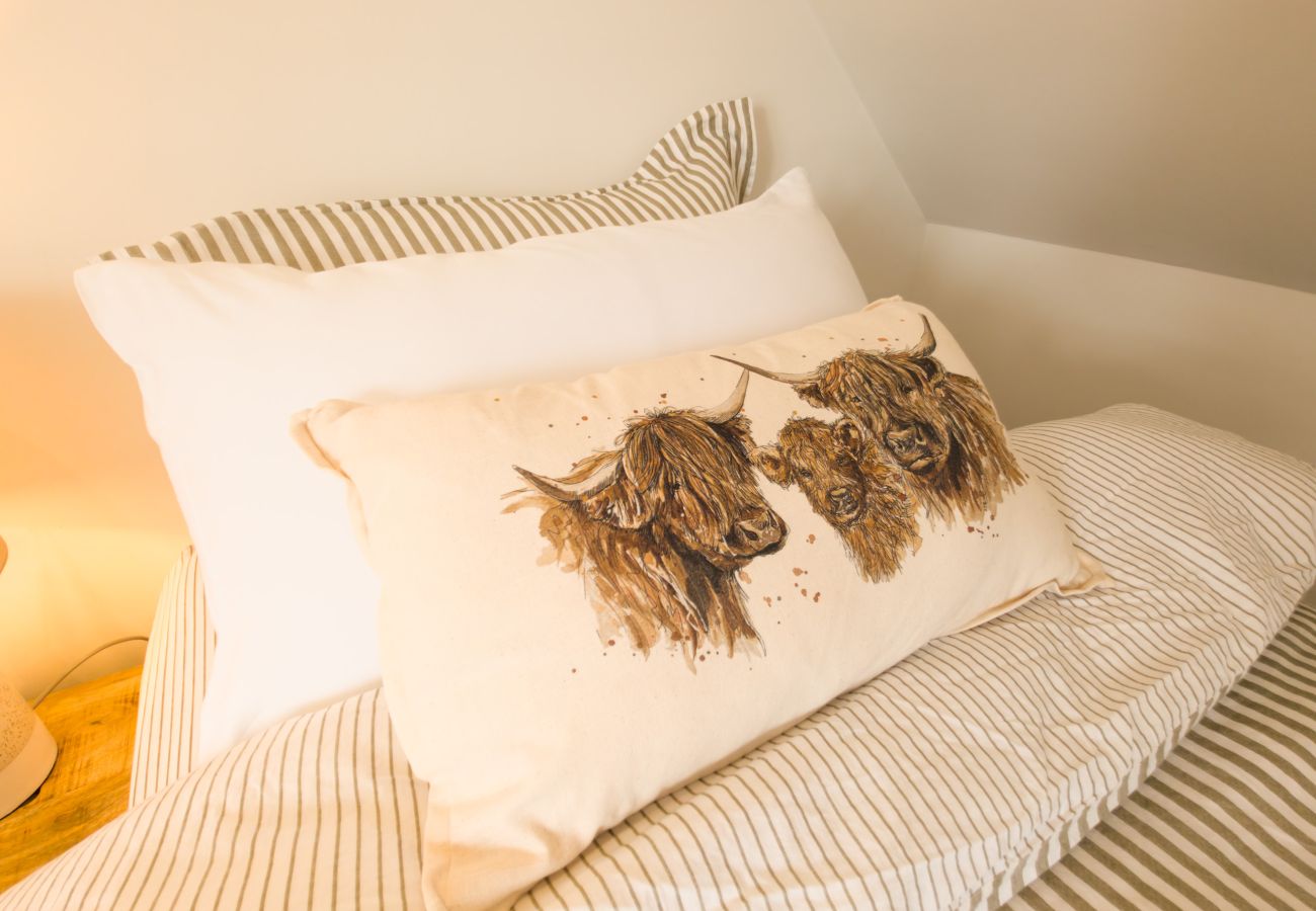 Cushion printed with Highland cows on a bed at Twinflower, Grantown-on-Spey in the Cairngorms